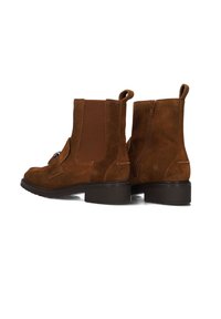 Bruine suède enkelbooties met elastische zijpanelen, een ritssluiting en een lage blokhak. Beschikt over een decoratieve gespsluiting.
