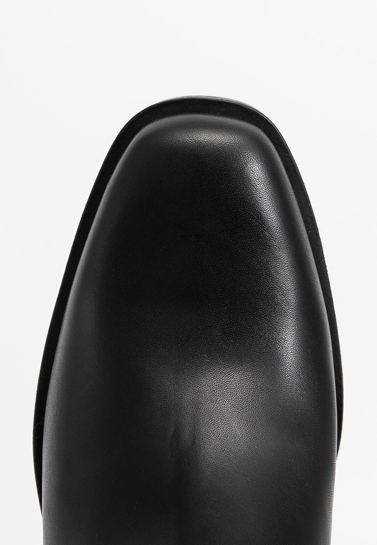 Schwarzer Lederschuh mit glatter Textur und einem runden Ze design. Verfügt über einen dezenten Glanz und minimale Akzente.