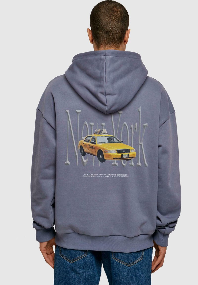 Felpa grigia con grafica di un taxi giallo e testo "New York" in un font più chiaro; materiale morbido con vestibilità rilassata e cappuccio.