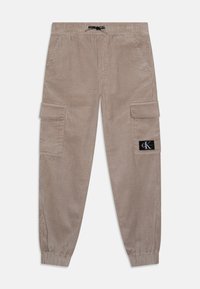 Beige korduroy cargo kalhoty s elastickým pasem, obsahující dvě boční kapsy a malou značkovou nášivku na levé noze.