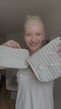 Δύο λευκά αξεσουάρ από ύφασμα με υφασμάτινη υφή, διαθέτουν μικρές κορδέλες και μηχανισμό κλεισίματος. Το ένα είναι ορθογώνιο, το άλλο ελάχιστα φαρδύτερο.