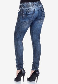 Schmale hellblaue Denim-Jeans mit einem verblassten und strukturierten Finish, dekorativen Nähten, fünf Taschen und einem hochgeschnittenen Design.