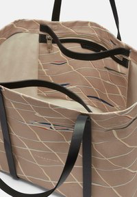 Borsa tote in tela con un motivo beige caratterizzato da sottili linee colorate. Manici in pelle nera e tasca con zip all'interno. Interno foderato.