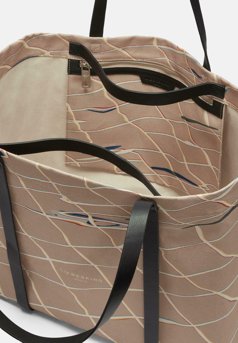 Canvas-Tasche mit einem beigen Muster, das dünne, bunte Linien zeigt. Schwarze Ledergriffe und ein Reißverschlusstasche im Inneren. Gefüttertes Innenleben.