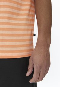 Short-sleeved orange and white striped t-shirt with a rounded hem, soft cotton material, and a small black label on the side seam.