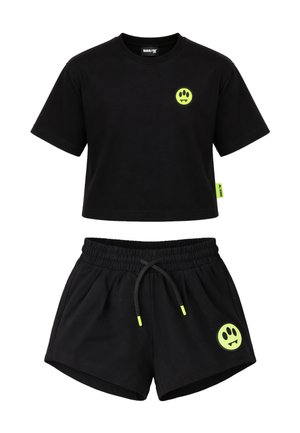 Top corto nero a maniche corte e pantaloncini con coulisse con loghi di faccine da vampiro neon verdi sul petto e sulla gamba.