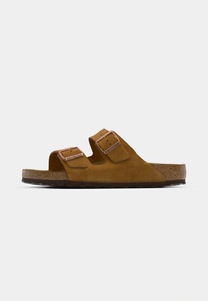 Brown suede slide sandal with two adjustable straps, cork footbed, and a textured rubber sole. Minimalist design with no additional embellishments.