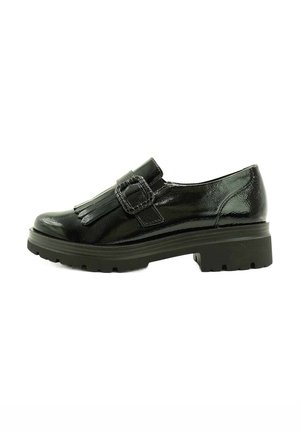 Zapato de cuero negro con un acabado brillante, que presenta una hebilla y un detalle de flecos. Tacón bajo con una suela texturizada. Vista lateral.