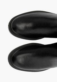 Svarta läderankelstövlar med en slät, blank yta och texturerad gummisula. Har en stilren form och subtila kantdetaljer.