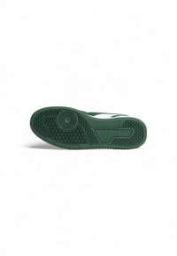 Suola di sneaker verde in gomma con un motivo di presa testurizzato e elementi di design circolari. Presenta un bordo superiore liscio e un'inserzione di branding stilizzata.