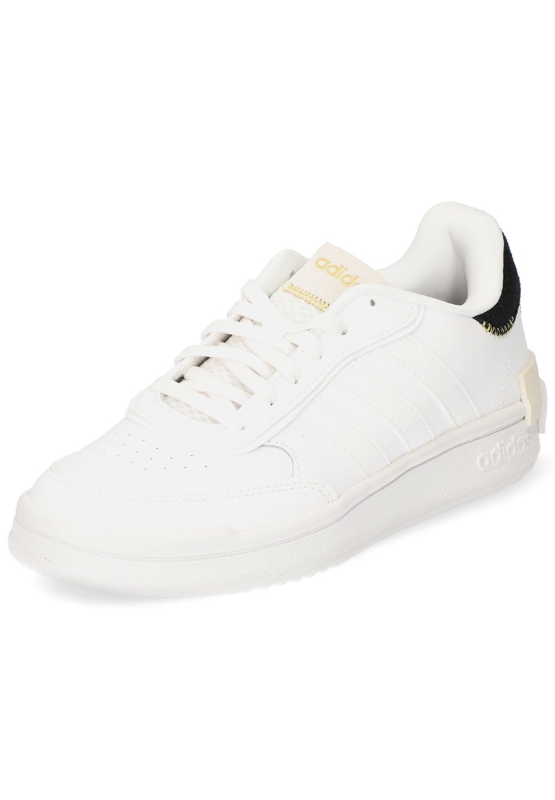 White leather sneaker with a textured surface, three parallel stripes, gold accents, and a black suede heel. Cushioned collar and rubber sole.