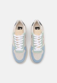 Baskets multicolores en mélange de suède et cuir perforé. Les couleurs incluent beige clair, vert, bleu et rose, avec des lacets blancs.