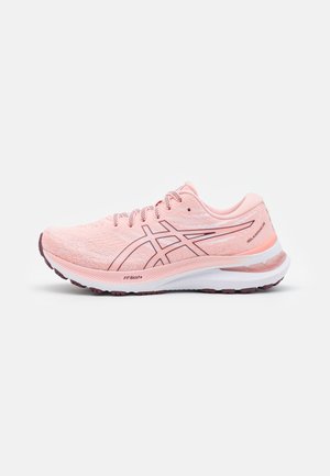 Zapatilla de running en rosa claro con parte superior texturizada, presenta acentos en blanco y rosa oscuro, suela acolchada y talón reforzado.