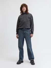 Γκρι υπερμεγέθη φούτερ με στρογγυλή λαιμόκοψη, σε συνδυασμό με μπλε ευθείες τζιν και σκούρα καφετιά παπούτσια με χοντρή σόλα. Απλή και χαλαρή εφαρμογή.