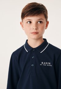 Jūras spēku polo krekls ar baltu apkakles detaļu un pogu rindām. Uz krūšu daļas ir logo "BAKER by TED BAKER" baltā krāsā. Mīksts audums.