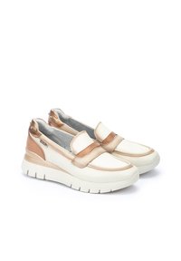 Chaussures slip-on avec un dessus beige et or métallisé, un col rembourré et une épaisse semelle en caoutchouc blanc avec des rainures texturées.