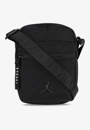 Čierna crossbody taška vyrobená z odolného materiálu, s vreckom na zips, textúrovaným popruhom s nápisom "JORDAN" a logom na prednej strane.