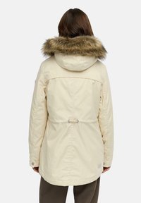 Crème-kleurige parka-jack met een gevoerde capuchon van nepbont, een getailleerde taille en knopenaccenten. Egaal textuur en een relaxte pasvorm.