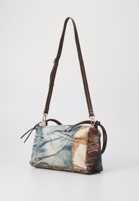 Sac bandoulière avec un motif en denim, accents en cuir marron, forme rectangulaire et détails de couture décoratifs. Bandoulière réglable incluse.