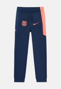 Marineblauwe sportbroek met een elastische tailleband, contrasterend koraalkleurig zijpaneel en logo's van FC Barcelona en Nike aan de voorkant.