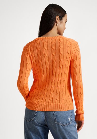 Camisola laranja de malha com cabo, de mangas compridas; com punhos e bainha canelados; usada com jeans azuis. A textura é grossa e padronizada.