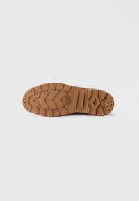 Suela de zapato de goma marrón con un patrón de agarre texturizado que presenta formas en zigzag y hexagonales, diseñada para ofrecer tracción y durabilidad.