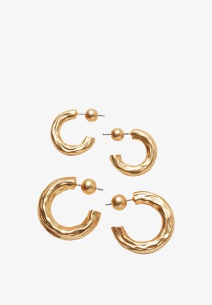 Quatre boucles d'oreilles en métal doré en forme de créoles avec une texture martelée et des têtes de clou rondes, sur un fond blanc, disposées avec deux paires plus petites et deux paires plus grandes.