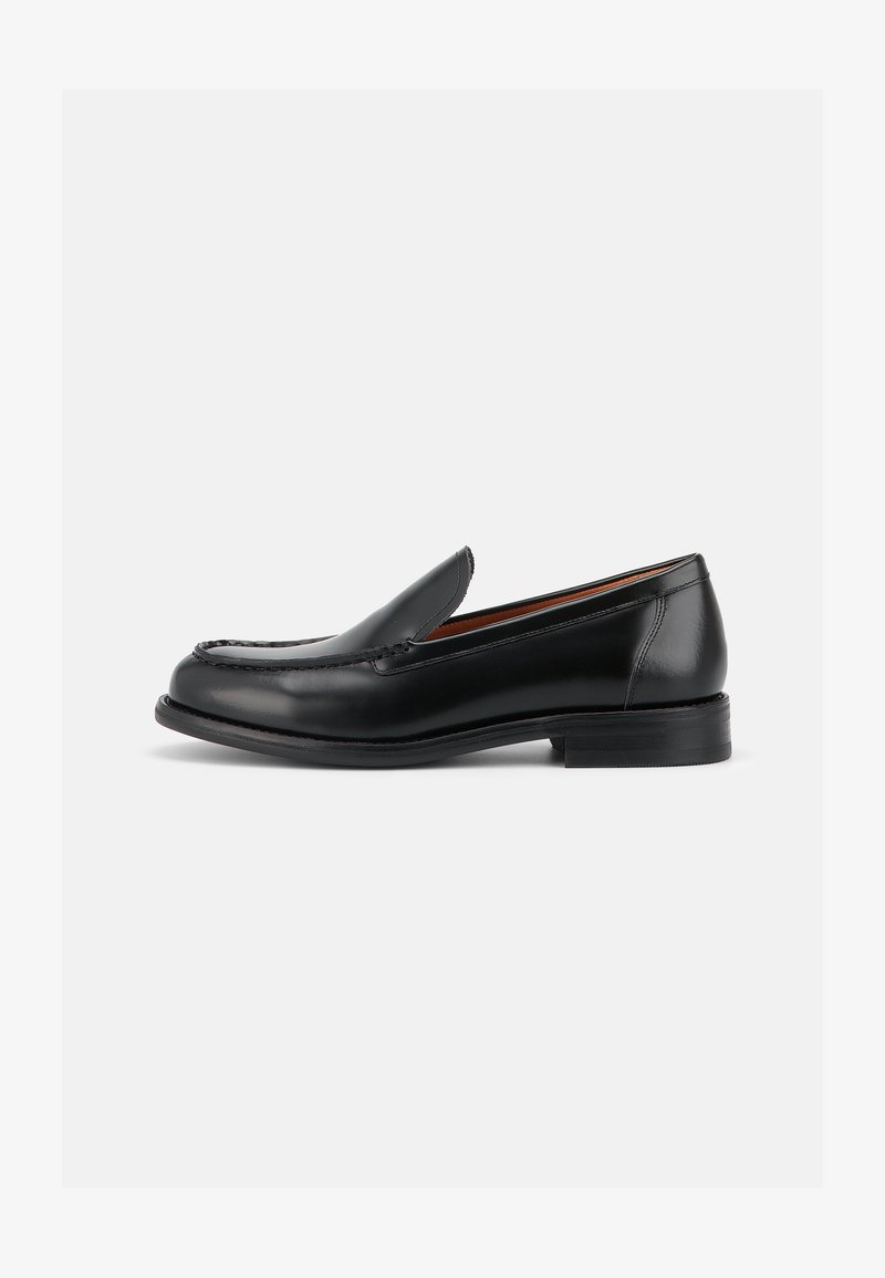 Mocassin en cuir noir à enfiler avec petit talon, bout arrondi et couture de style mocassin sur le dessus, vu de l'extérieur.