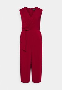Combinaison sans manches rouge avec un design enveloppant, détail de taille à nouer et une silhouette large et cropped, fabriquée à partir d'un tissu lisse.