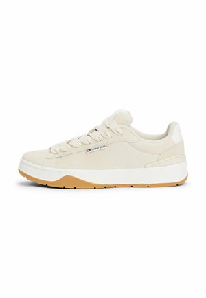 Baskets en daim beige avec lacets crème, semelle intermédiaire blanche et semelle extérieure en caoutchouc nature. Présente un design minimaliste et un petit détail de logo sur le côté.
