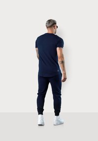 Navy cotton t-shirt with short sleeves, rounded hem, and slim-fit design, paired with matching joggers and white sneakers.