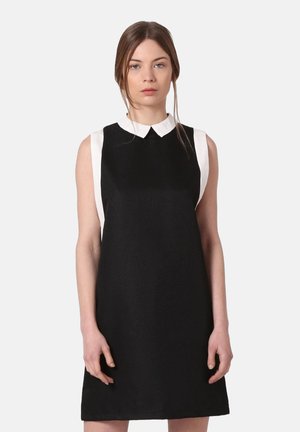 Vestido negro sin mangas con un cuello blanco, corte recto, tejido texturizado y diseño minimalista. Sin patrones visibles ni adornos.