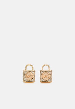 Kulta sävyiset padlock-korvakorut, joissa on keskeinen logo ja kimaltelevat kristallikoristeet, pyöreä yläosa ja teksturoitu runko.