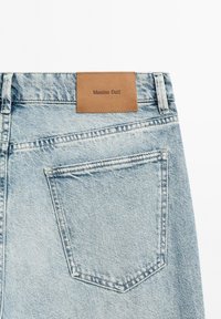 Blue denim jeans featuring a brown leather label with "Massimo Dutti" embossed. Includes a back pocket with a classic cut and stitching detail.