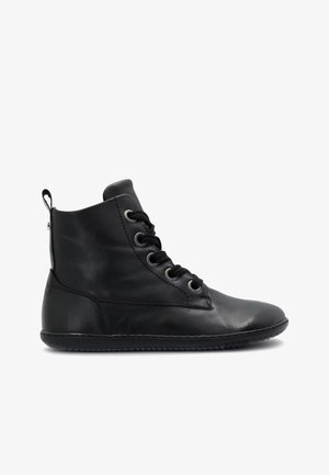 Bottine en cuir noir avec lacets sur le devant, languette au talon et semelle flexible, présentée en profil sur fond blanc.