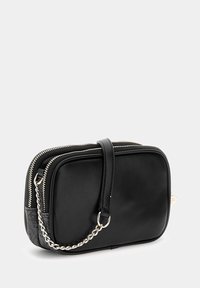 Borsa a tracolla nera in pelle con forma rettangolare, chiusura con zip, tracolla a catena e un dettaglio grigio testurizzato su un lato.