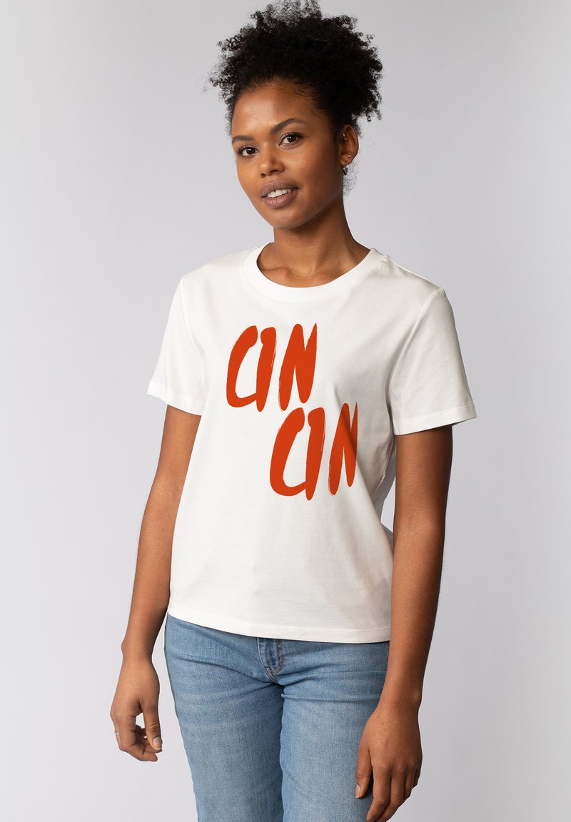 Witte katoenen T-shirt met dikke rode "CIN" tekst. Korte mouwen en ronde hals, in combinatie met lichtblauwe denim jeans.