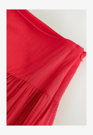 Punase kanga kleidi lähedalt vaadatuna, kus vöö all on kortsudega õmblus ja külje peal punase tõmblukuga tõmmitsa