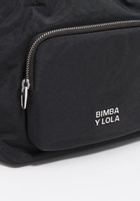 Czarna nylonowa torba z zamkiem błyskawicznym, posiadająca teksturowaną powierzchnię oraz srebrne logo "BIMBA Y LOLA" na przedniej kieszeni.
