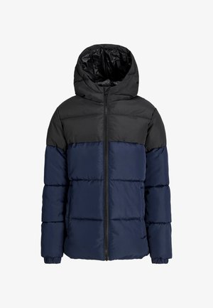 Puffer jacket with a black top half and navy bottom half, featuring a hood. Paired with light blue jeans and beige shoes.