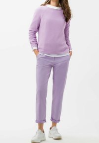 Ljuslila stickad tröja med ribbad textur, lager på lager över en vit skjorta, parat med ljuslila chinos och vita sneakers.