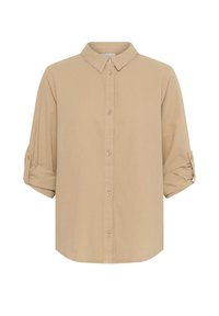 Chemise beige à manches longues boutonnée, avec col et manches retroussées maintenues par des pattes avec boutons.