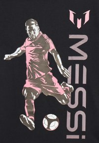 Mustapaita, jossa on grafiikka vaaleanpunaisessa ja harmaassa, esittäen pelaajaa potkaisemassa jalkapalloa, ja "MESSI" on tulostettu pystyyn vastaavalla vaaleanpunaisella.