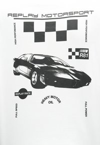 Baltas T-krekls ar melnu sporta automobiļa grafiku, akcentēts ar šaha karogiem un tekstu, tajā skaitā "REPLAY MOTORSPORT" un "HEAVY MOTOR OIL."
