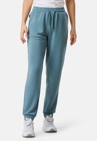 Helle blaue Jogginghosen mit lockerer Passform, elastischem Bund und Kordelzug. Weicher Stoff mit Bündchen an den Knöcheln und Seitentaschen.