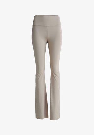 Leggings évasés beiges en matériau extensible. Taille haute avec une marque discrète. Texture lisse sans coutures ni motifs visibles.