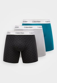 Calvin Klein boxeralsók három színben: fekete geometrikus mintával, szürke és türkiz. Mindegyik fekete márkás derékpánttal rendelkezik.
