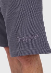 Grau strukturierte Shorts mit einem gerippten Design. Verfügt über ein gesticktes "Dropsize"-Logo am Saum, abgeschlossen mit einem sauberen, genähten Rand.