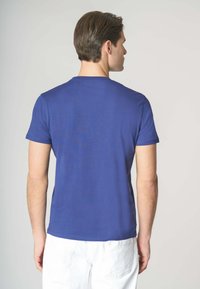T-shirt in cotone blu con maniche corte e scollatura rotonda, caratterizzato da una texture liscia e un design aderente, mostrato di spalle.