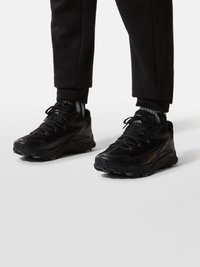 Black athletic shoes with a textured mesh upper, reinforced toe, and rubber outsole. Features laces and padded collar for comfort.